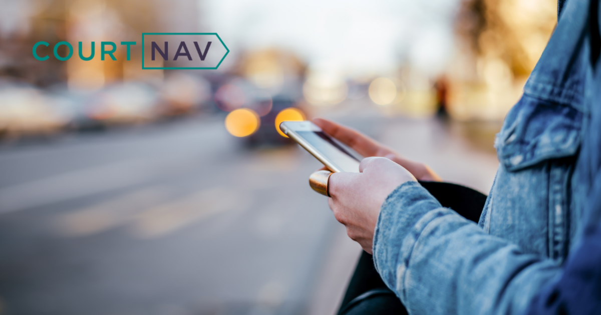 Woman in a denim jacket standing at the side of a road using her mobile phone. The image has the Court Nav logo in the top left corner.